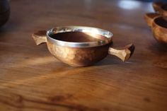 a wooden bowl sitting on top of a wooden table next to a metal cup holder