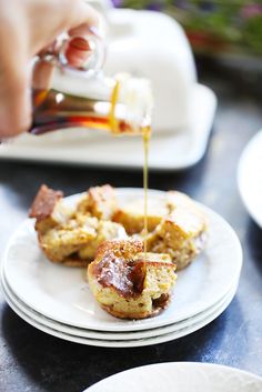 someone pouring syrup on some food on a plate