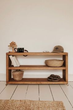 a wooden shelf sitting on top of a white floor next to a basket and hat