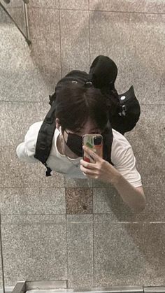 a woman taking a selfie in the mirror on her cell phone while standing next to an escalator