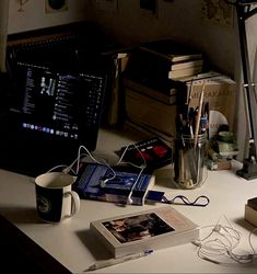 a desk with a computer monitor, books and other items on it next to a lamp