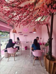 two women sitting in pink chairs under a tree with pink flowers on the ceiling and windows