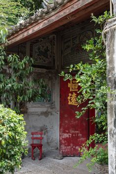 a red bench sitting in front of a building with chinese writing painted on it's doors