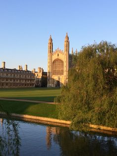 a large building sitting on top of a lush green field next to a body of water