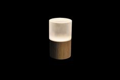 a white light sitting on top of a wooden table next to a black wall in the dark