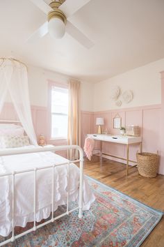 a white bed sitting in a bedroom next to a pink dresser and lamp on top of a hard wood floor