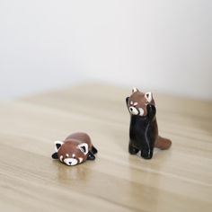 two toy raccoons sitting on top of a wooden table