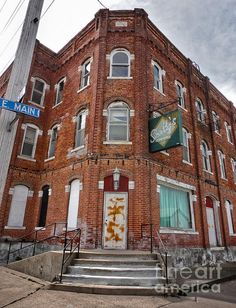 an old red brick building with stairs leading up to the front door and sign above it