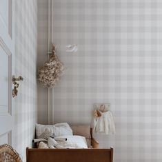 a baby's crib in the corner of a room with plaid wallpaper