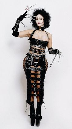 a woman with black hair and makeup wearing a corset, holding scissors in her hands