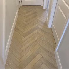 an empty hallway with white doors and wood flooring on either side of the door