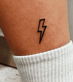 a person with a small tattoo on their leg that has a lightning bolt in it