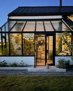 a house that is lit up at night with lights on the windows and plants growing outside