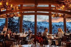 people sitting at tables in a restaurant with mountains in the background