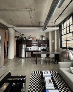 a living room filled with furniture next to a kitchen and dining room table covered in black and white checkered rugs