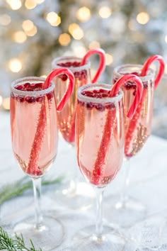 three glasses filled with pink liquid and candy canes