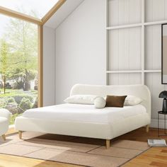 a white bed sitting in the middle of a room next to a large glass window