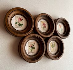 four wooden bowls with flowers painted on them are arranged in a pattern and placed on the wall