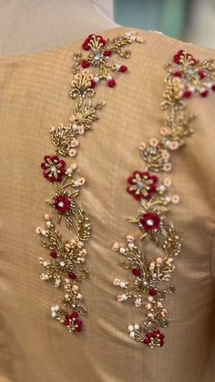 the back of a woman's dress with red and white beading on it