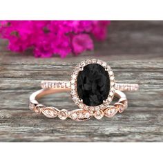 a black and white diamond engagement ring set on top of a wooden table with flowers in the background