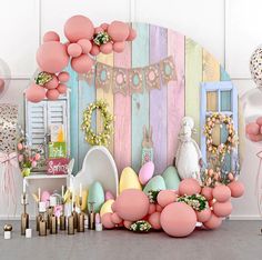 an assortment of balloons and decorations on display in front of a wooden wall with pastel colors