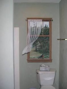 a bathroom with a toilet, window and painting on the wall