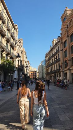 two women walking down the street in front of buildings