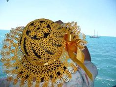 a woman wearing a yellow hat with a bow on it's head looking out at the ocean