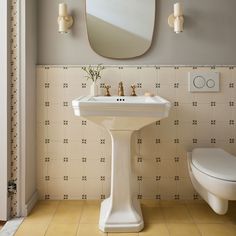 a white pedestal sink sitting next to a toilet in a bathroom under a large mirror