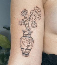 a woman with a tattoo on her arm has a vase filled with flowers and leaves