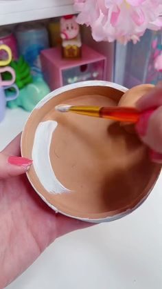 a person holding a paintbrush in their hand and painting the inside of a bowl