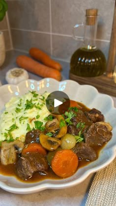 a white plate topped with meat and veggies covered in gravy next to carrots