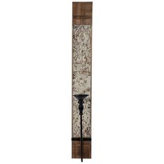 a tall wooden pole with a black candle on it's end and an ornate wallpaper behind it