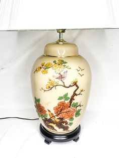 a lamp that is sitting on top of a white surface with flowers and birds painted on it