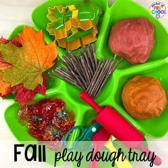 a green tray filled with different types of playdoughrays on top of a white table