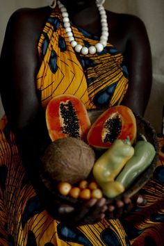 a woman holding a bowl filled with fruits and vegetables