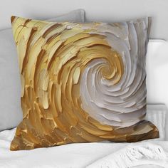 a white and gold pillow on top of a bed