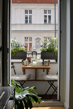 an open door leading to a balcony with two chairs and a table in front of it