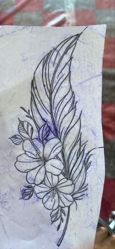 a piece of paper with a drawing of a feather and flowers on it's side