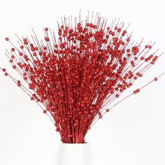 a white vase filled with red flowers on top of a table