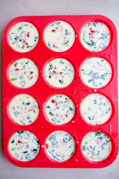 a muffin tin filled with cupcakes covered in white sauce and toppings