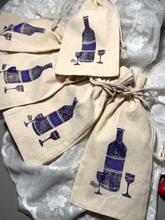 four wine bags with bottles and glasses printed on them, tied to a white lace table cloth