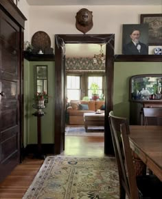 a living room filled with furniture and pictures on the wall next to a doorway that leads into a dining room