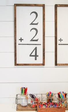 two framed numbers are on the wall next to some pens and pencils in baskets