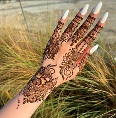 a woman's hand with henna on it and some grass in the background