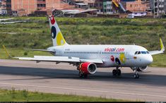 an airplane on the runway with buildings in the backgrouds and grass behind it