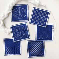 four blue square coasters with white stitching on them