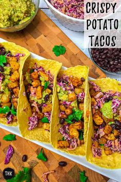 three tacos filled with chicken, black beans and coleslaw on top of a cutting board