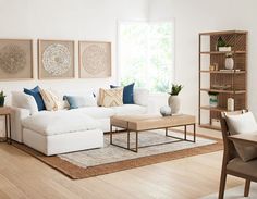 a living room with white couches and wooden tables in front of a large window