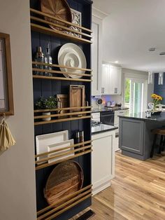 a kitchen with wooden flooring and white cupboards filled with dishes on top of shelves